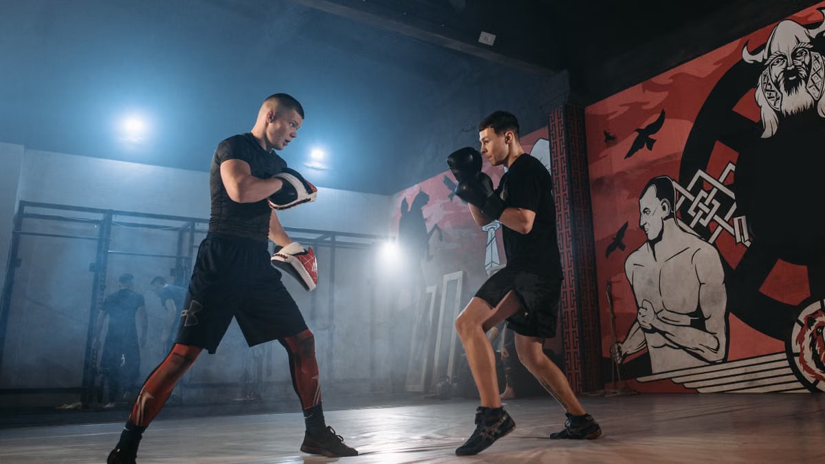 Focused boxers engage in intense mitt drills within a gym setting, highlighting the essence of combat sport training.